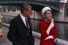 Audrey Hepburn (right) holds a chocolate ice cream cone and walks down the Paris streets alongside Cary Grant in a still from Charade.